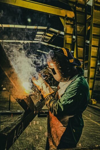 A skilled welder works on metal fabrication in a Brazilian factory, showcasing industrial precision.